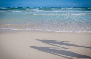 Silhouette of a couple's shadow on Tulum's white sand beach with the ocean in the background